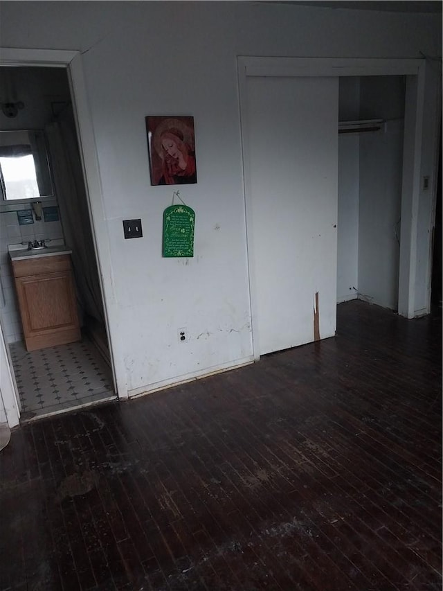 unfurnished bedroom featuring dark hardwood / wood-style flooring and connected bathroom