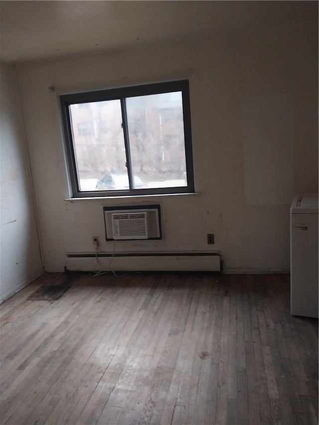 unfurnished room with washer / clothes dryer, light wood-type flooring, baseboard heating, and a wall unit AC