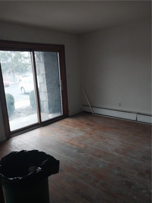 unfurnished room with hardwood / wood-style flooring and a baseboard heating unit