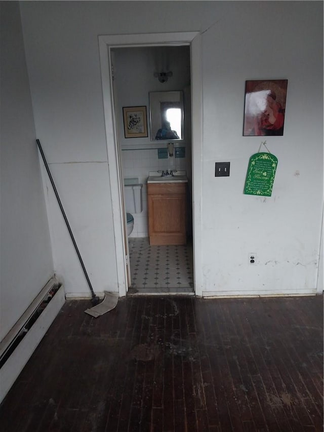 hallway with sink, dark hardwood / wood-style flooring, and a baseboard heating unit