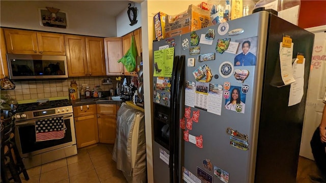 kitchen with tile patterned floors, decorative backsplash, sink, and stainless steel appliances