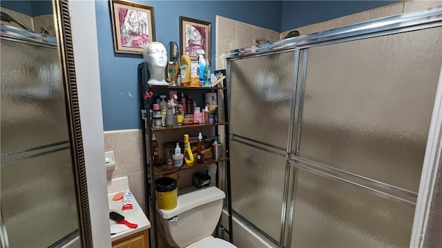 bathroom with toilet and combined bath / shower with glass door