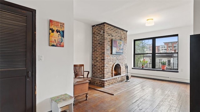 living room with hardwood / wood-style flooring, a fireplace, and baseboard heating