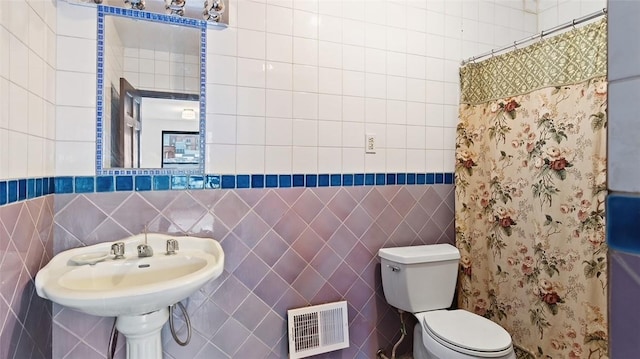 bathroom with toilet and tile walls