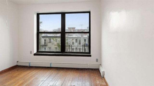 empty room featuring hardwood / wood-style floors and baseboard heating