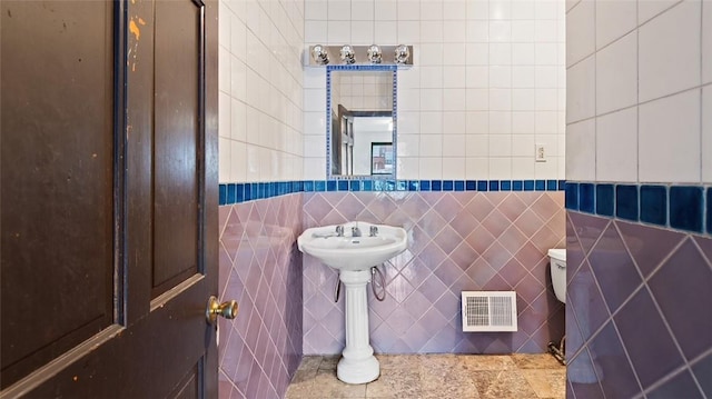 bathroom with tile walls and toilet