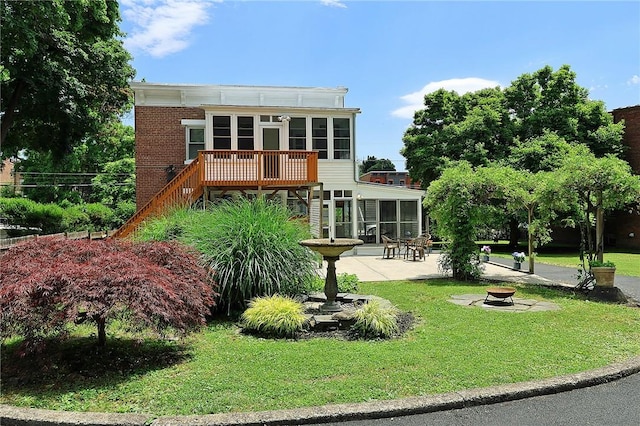 rear view of house with a fire pit, a sunroom, a deck, and a patio