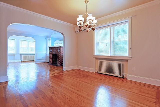 interior space with radiator heating unit, an inviting chandelier, hardwood / wood-style floors, and a brick fireplace