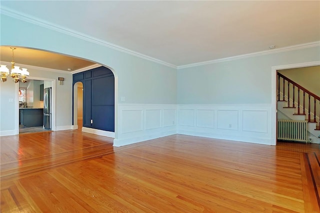 unfurnished room featuring radiator heating unit, a notable chandelier, ornamental molding, and hardwood / wood-style floors