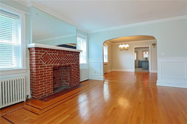 unfurnished living room with wood-type flooring, radiator, and crown molding