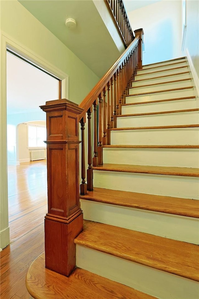 stairway featuring hardwood / wood-style floors and radiator heating unit