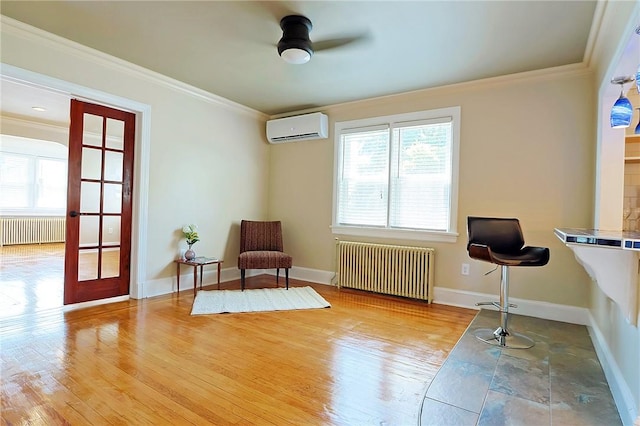 living area featuring radiator heating unit, ornamental molding, a wall unit AC, and light hardwood / wood-style flooring