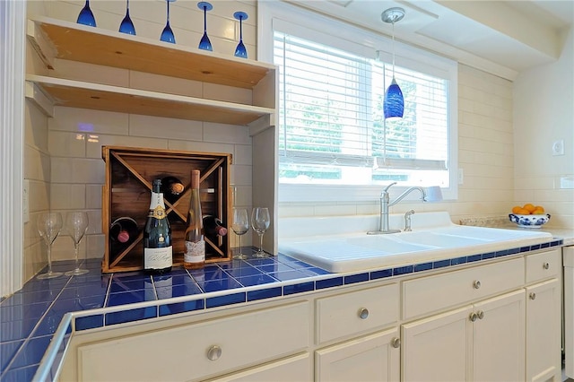 kitchen featuring decorative backsplash, tile countertops, white cabinetry, and hanging light fixtures