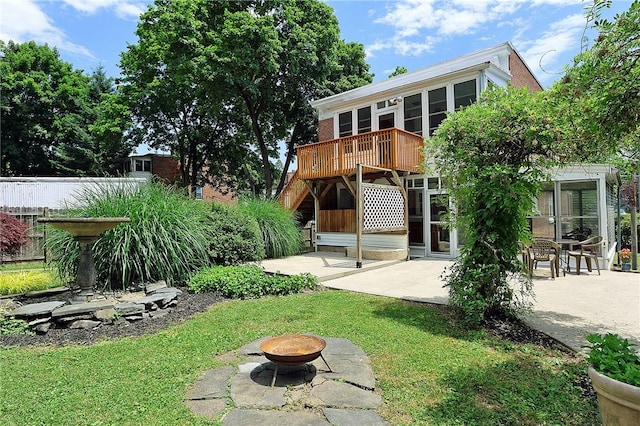 back of house with a yard, a deck, an outdoor fire pit, and a patio area