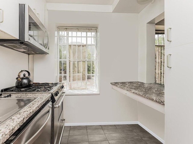 kitchen with white cabinets, plenty of natural light, appliances with stainless steel finishes, and dark tile patterned flooring