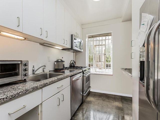 kitchen with white cabinets, stainless steel appliances, stone counters, and sink