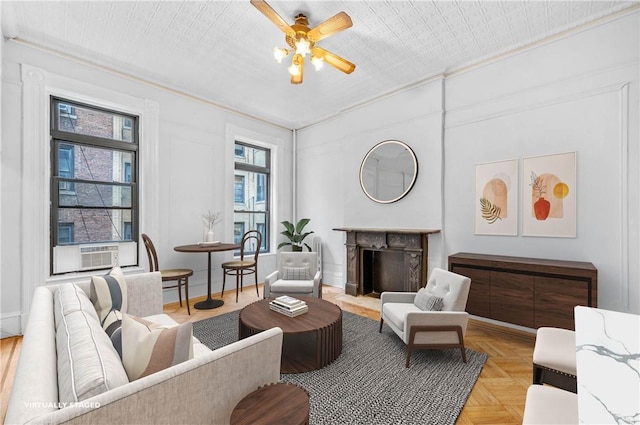 living area featuring ceiling fan, cooling unit, ornamental molding, and light parquet floors