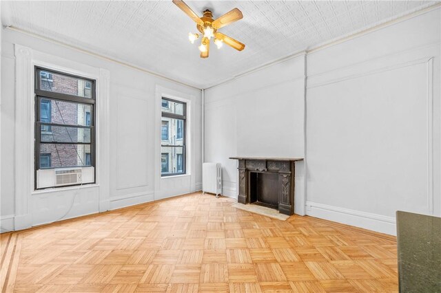 unfurnished living room with cooling unit, ceiling fan, radiator heating unit, and light parquet flooring