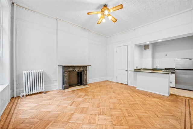 unfurnished living room featuring ceiling fan, radiator, and light parquet flooring