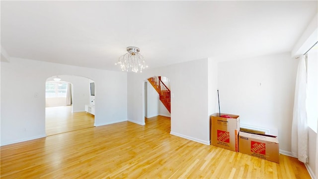 spare room featuring wood-type flooring and a notable chandelier