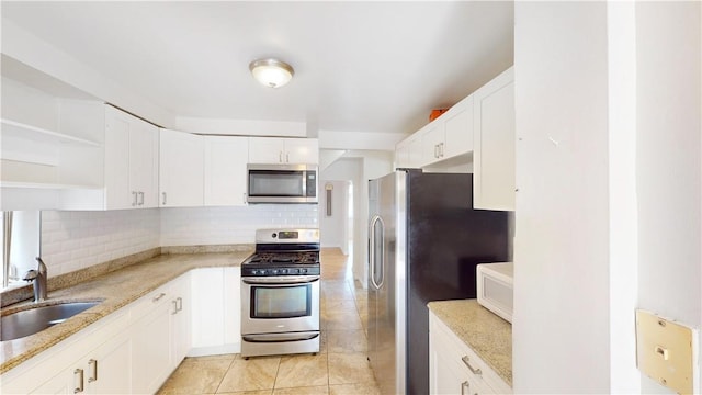 kitchen with tasteful backsplash, sink, white cabinets, and stainless steel appliances