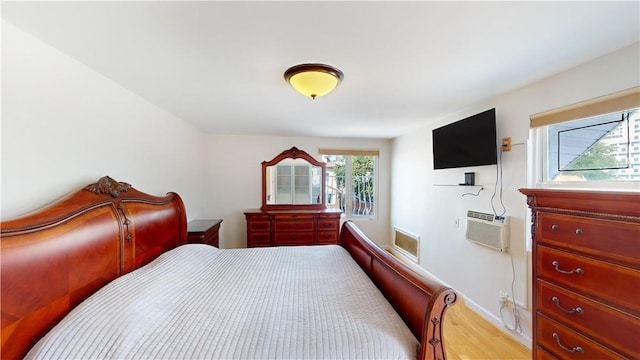 bedroom with light hardwood / wood-style flooring and a wall unit AC