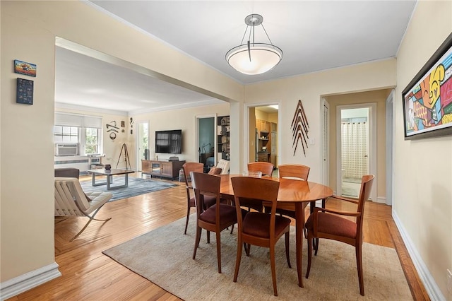 dining space with cooling unit, light wood-type flooring, and ornamental molding