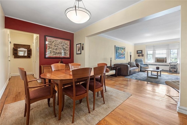 dining area with cooling unit, light wood-type flooring, and crown molding