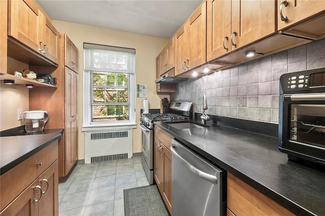 kitchen with decorative backsplash, stainless steel appliances, sink, light tile patterned floors, and radiator heating unit