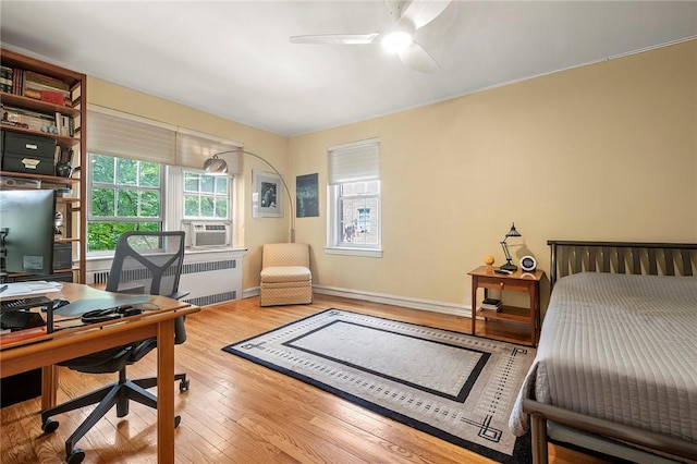 office space featuring light hardwood / wood-style floors, radiator, cooling unit, and ceiling fan