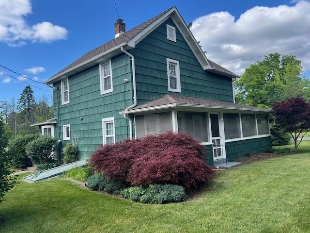 view of property exterior featuring a lawn and a sunroom