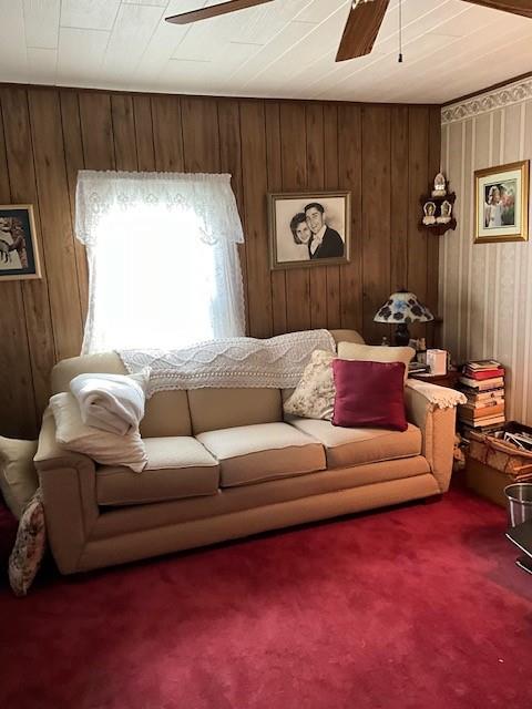 living room featuring carpet floors, ceiling fan, and wood walls