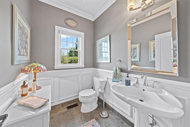 bathroom featuring toilet, crown molding, and sink