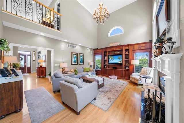 living room with french doors, a towering ceiling, light hardwood / wood-style flooring, and a notable chandelier