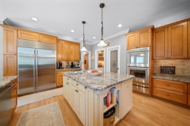 kitchen featuring stainless steel appliances, sink, a center island with sink, light hardwood / wood-style floors, and hanging light fixtures