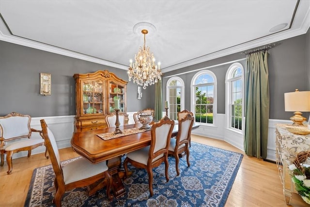 dining space with light hardwood / wood-style floors, an inviting chandelier, and crown molding