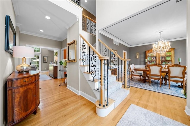 stairway featuring hardwood / wood-style flooring, crown molding, and an inviting chandelier