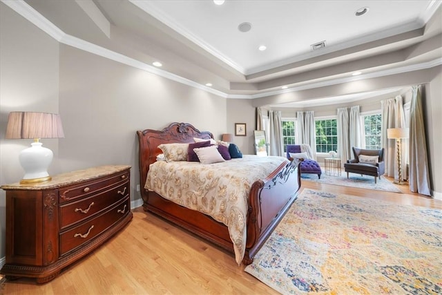 bedroom with light hardwood / wood-style floors, a tray ceiling, and crown molding