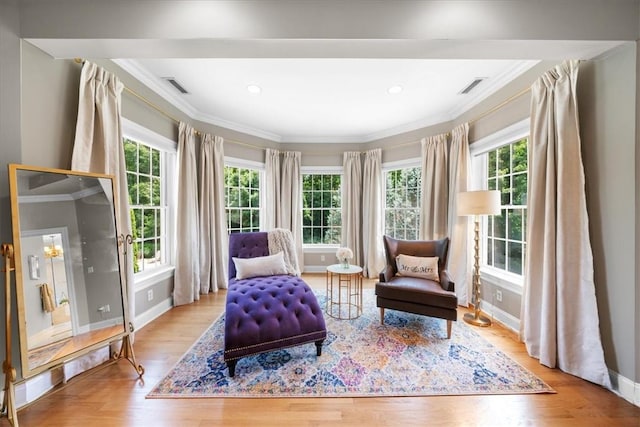 sitting room with ornamental molding and light wood-type flooring