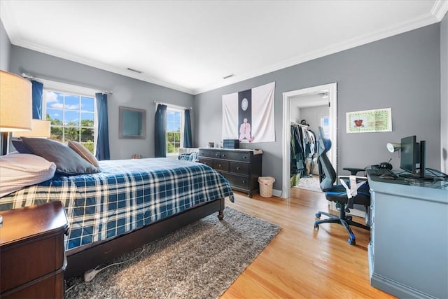 bedroom featuring hardwood / wood-style floors, a walk in closet, a closet, and ornamental molding