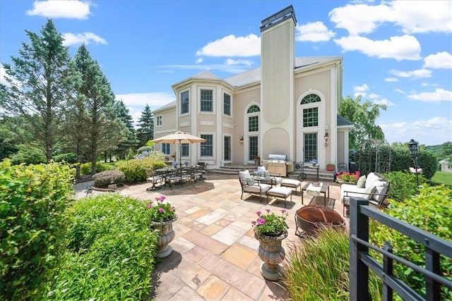 rear view of house featuring a patio and an outdoor living space with a fire pit