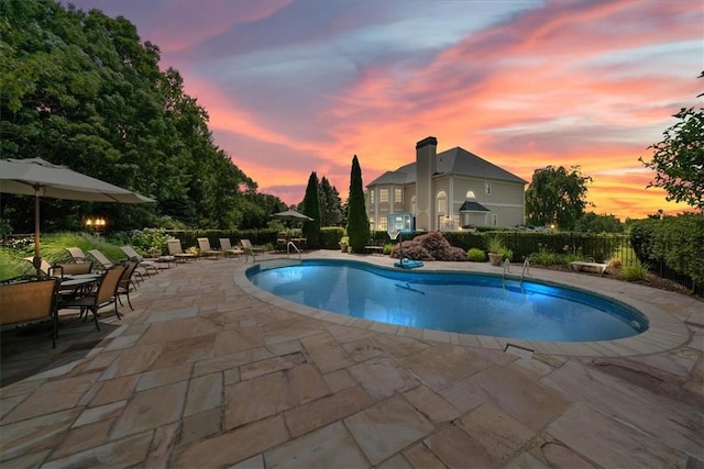 pool at dusk featuring a patio