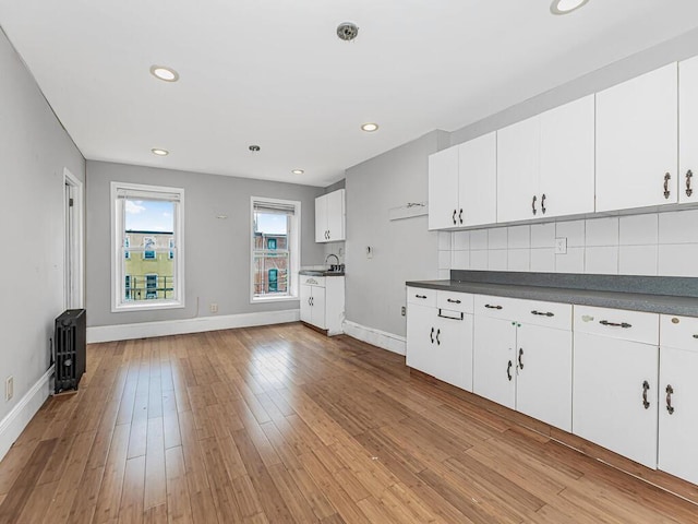 kitchen featuring white cabinets, decorative backsplash, and light hardwood / wood-style flooring