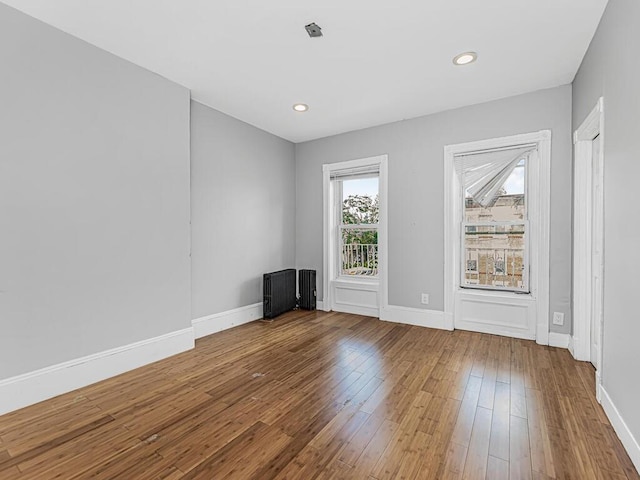 unfurnished room with radiator and hardwood / wood-style floors