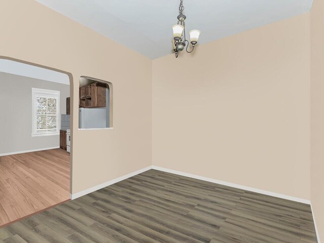 unfurnished room with dark hardwood / wood-style flooring and an inviting chandelier