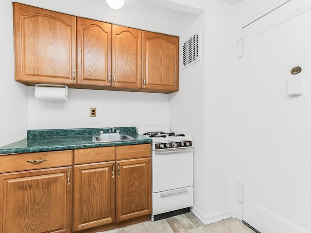 kitchen featuring sink, light tile patterned flooring, and white range