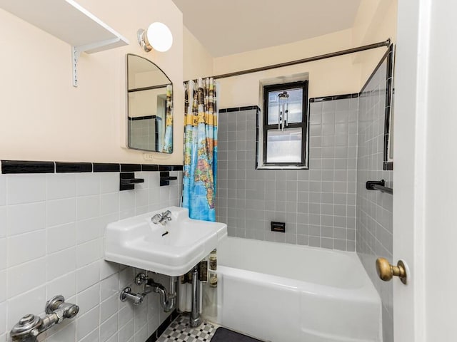 bathroom with tile patterned floors, shower / bath combination with curtain, sink, and tile walls