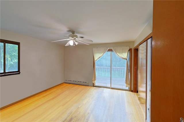 spare room featuring hardwood / wood-style flooring, baseboard heating, a healthy amount of sunlight, and ceiling fan