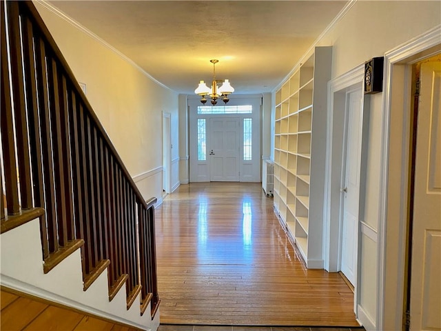 entryway featuring ornamental molding, a notable chandelier, and light wood-type flooring