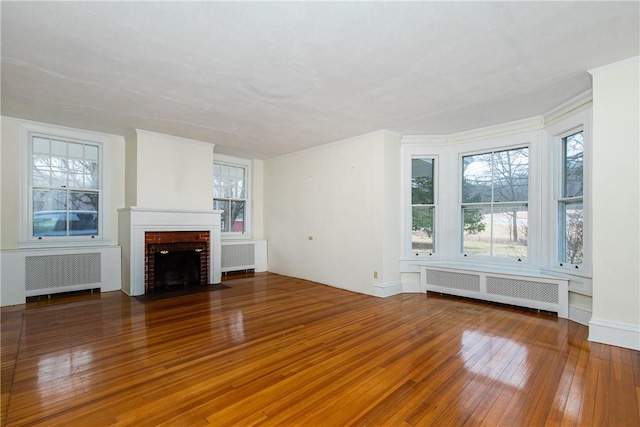 unfurnished living room with a fireplace, radiator heating unit, and hardwood / wood-style floors